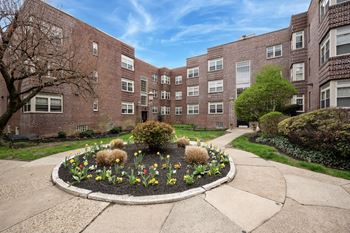 A brick building with a flower bed in front.